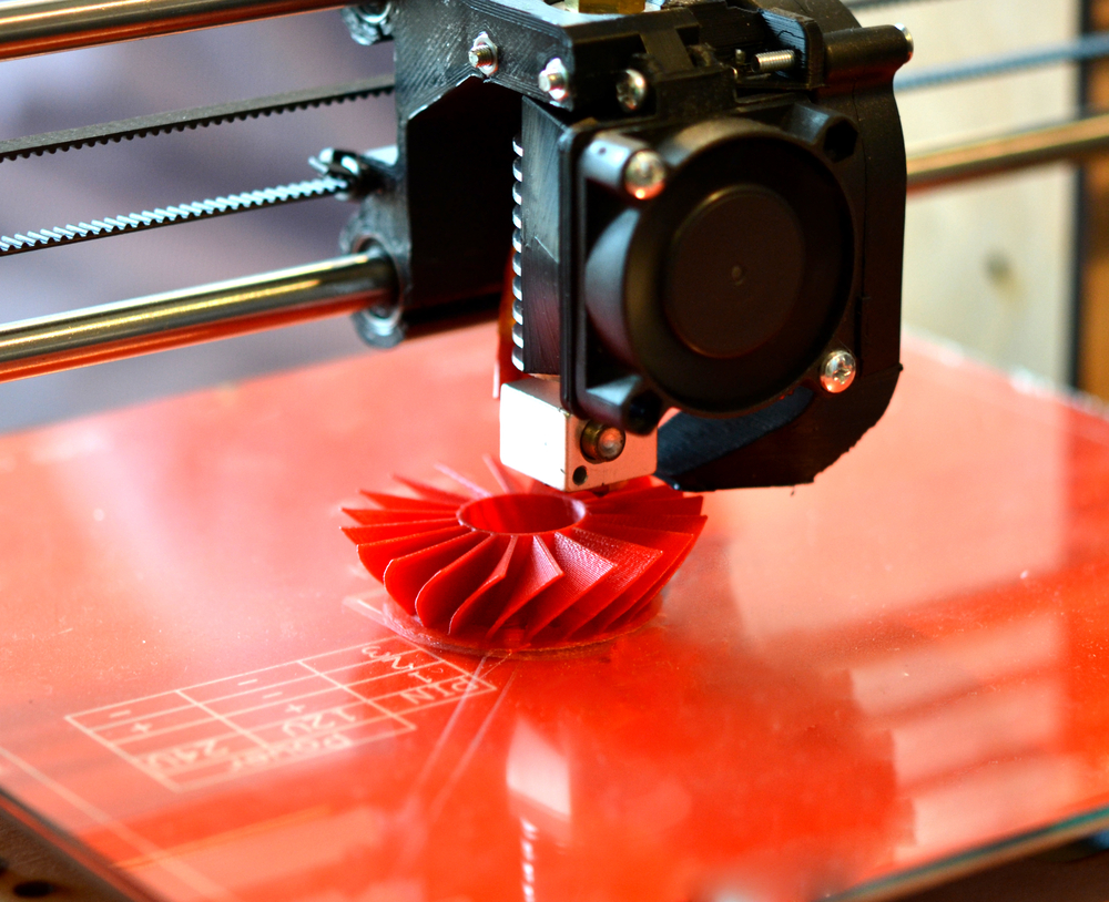 3D Printer printing red object.